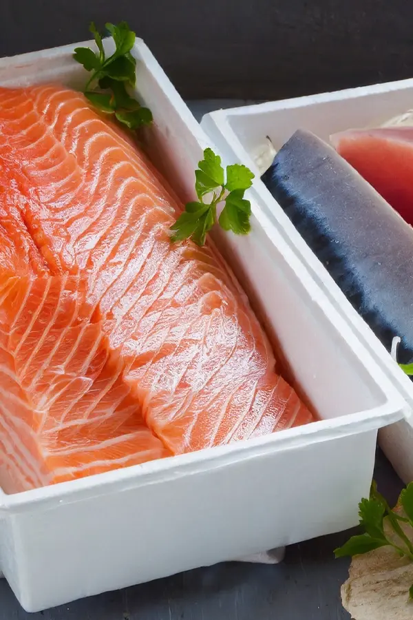 Fresh salmon and tuna fillets displayed in insulated shipping boxes